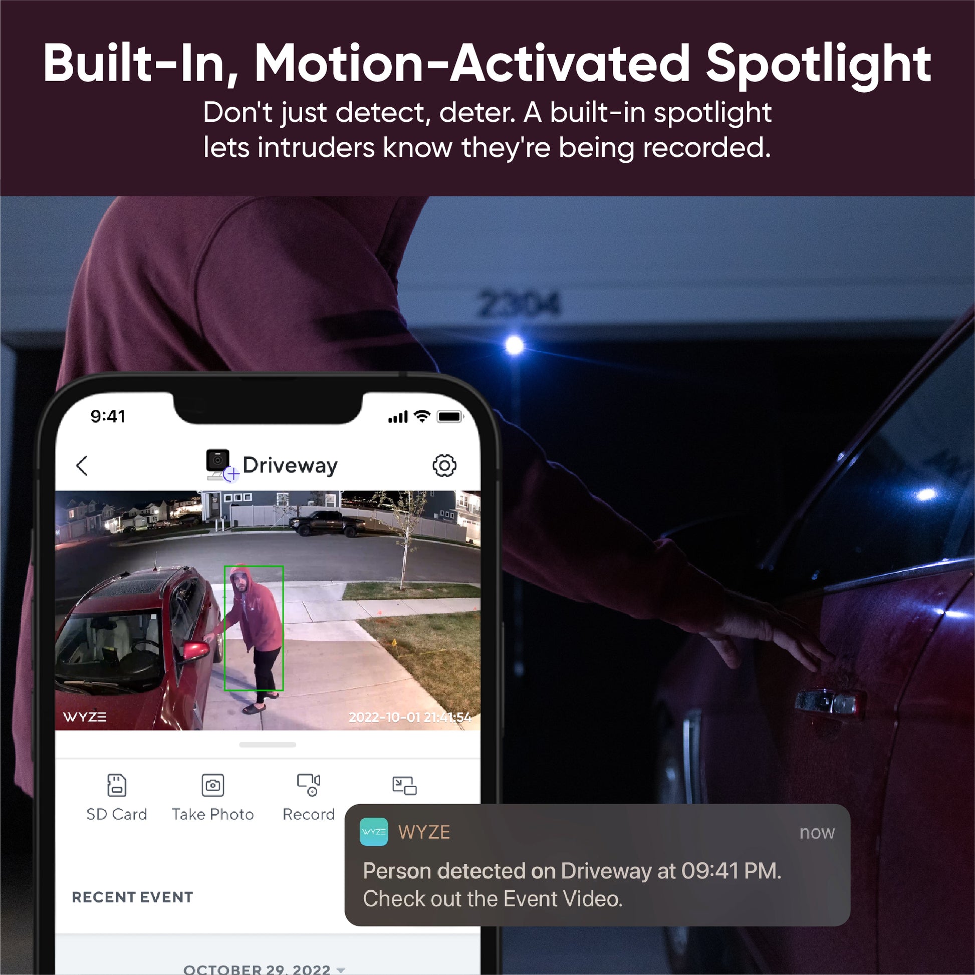 Wyze app on smartphone showing image of a person opening a car. Text overlay "Built-in, Motion-Activated Spotlight."