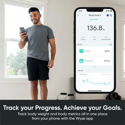 Man standing on scale and looking at phone. Phone screen shows scale data in Wyze app. Text overlay says "Track body weight and body metrics all in one place from your phone with the Wyze app."